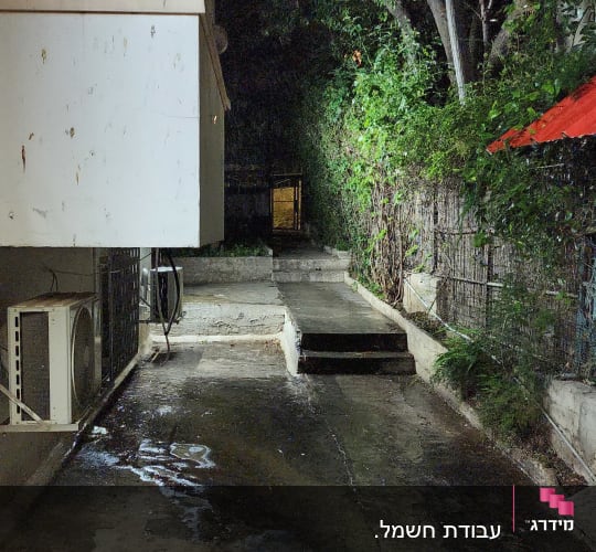 יחידת מיזוג אוויר מותקנת ליד שביל חיצוני